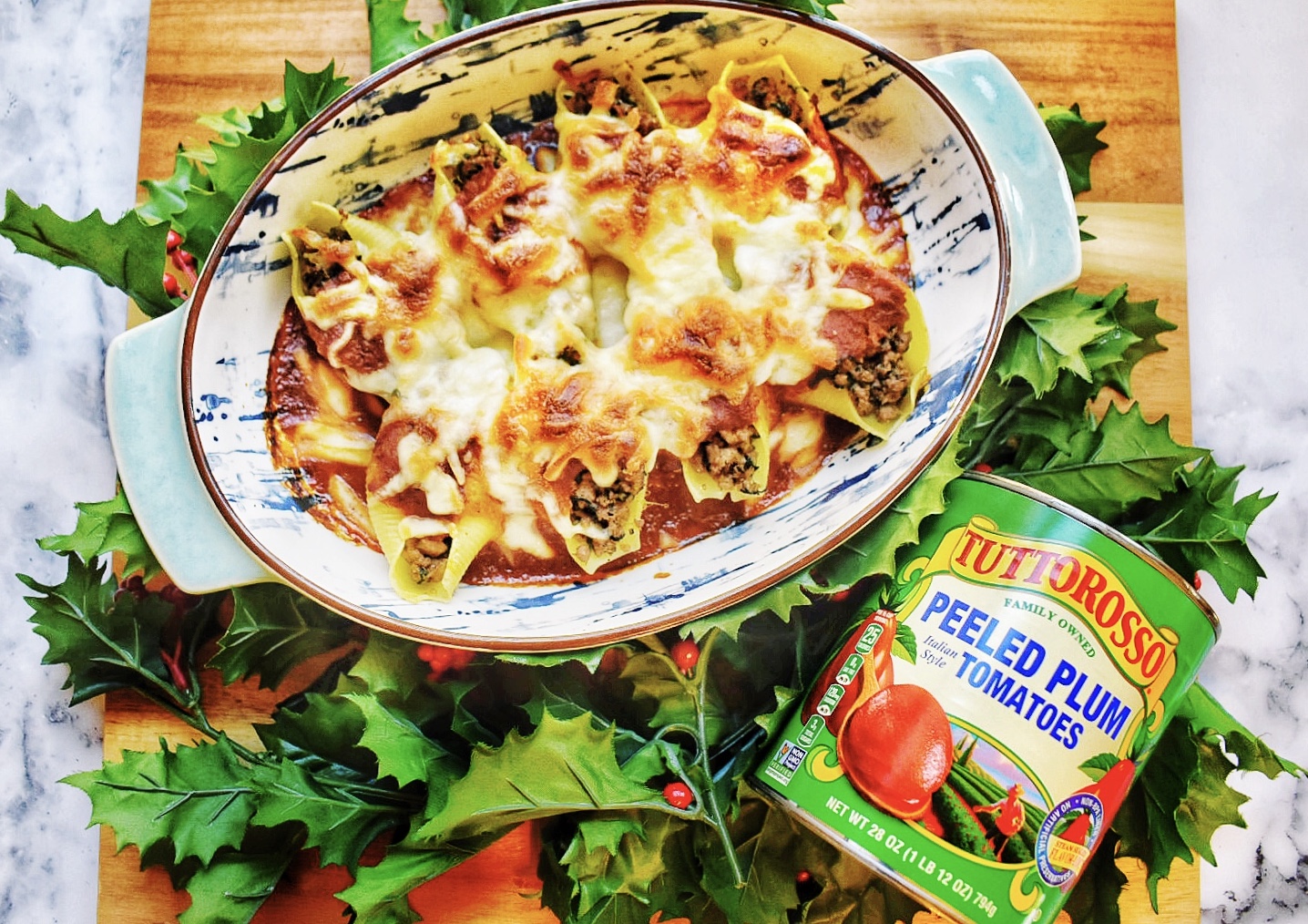 Stuffed shells with meat and cheese with tomato sauce in a blue splattered patter with holly and a Tuttorosso tomato can.